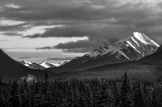 grayscale photography of snow covered mountain under cloudy sky